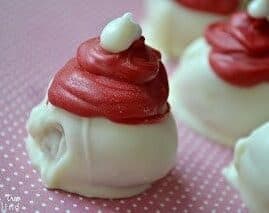 White Chocolate Raspberry Oreo Truffles are flavored with raspberry extract and decorated to look like adorable little Santa hats!