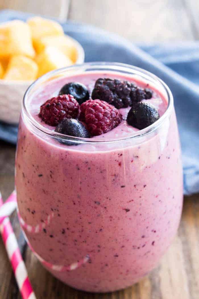 mango-berry smoothie in a glass garnished with fresh berries