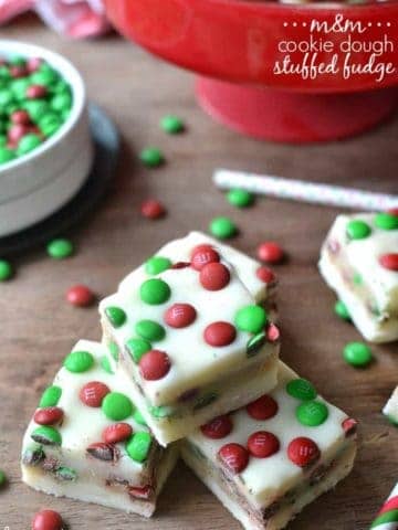 M&M Cookie Dough Stuffed Fudge is an easy, delicious recipe thats perfect for the holidays. This 5 minute fudge is made with white chocolate stuffed with an M&M cookie dough and topped with more M&M's! A crowd pleaser and a great gift!