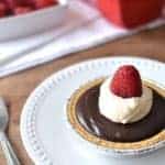 These Chocolate Ganache Tarts are topped with fresh orange whipped cream and raspberries.
