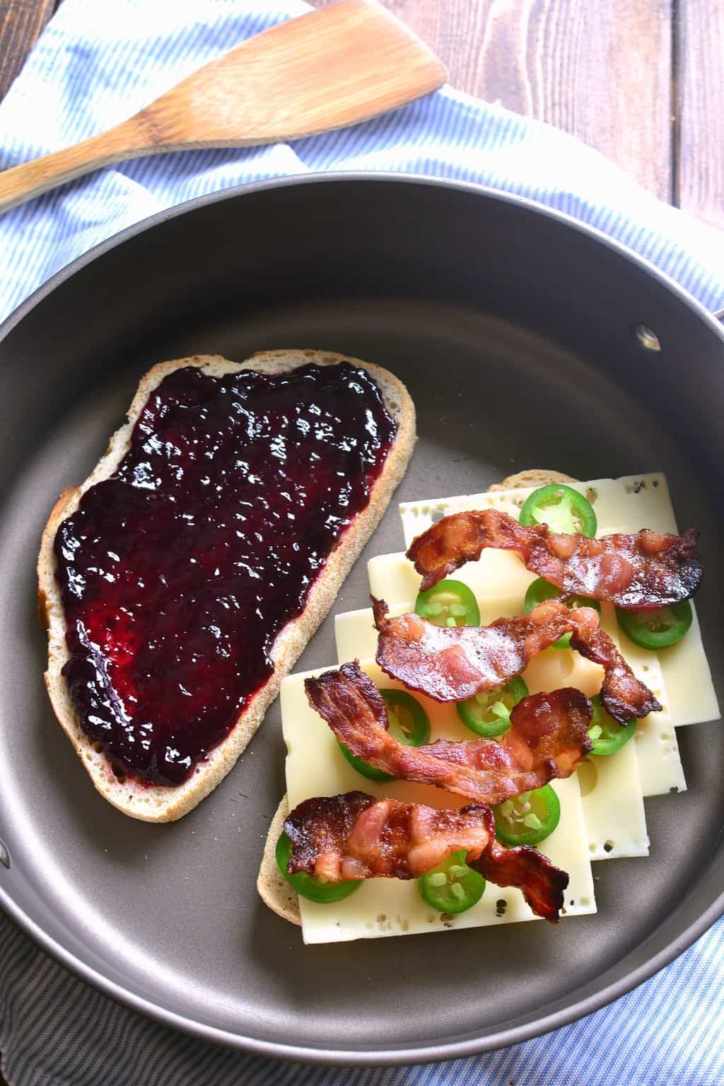 Blackberry Bacon Grilled Cheese is the perfect combination of savory and sweet! Made with Swiss cheese, blackberry jam, fresh jalapeños, and crispy bacon, it's a must try for ALL sandwich lovers! Blackberry Bacon Grilled Cheese sandwich cooking in a frying pan