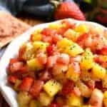 overhead image of a bowl filled with fresh fruit salsa garnished with poppy seeds