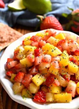 overhead image of a bowl filled with fresh fruit salsa garnished with poppy seeds
