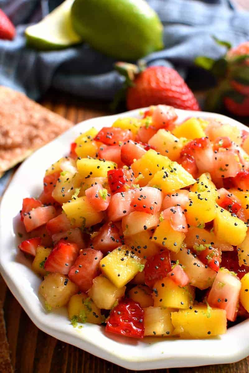 overhead image of a bowl filled with fresh fruit salsa garnished with poppy seeds