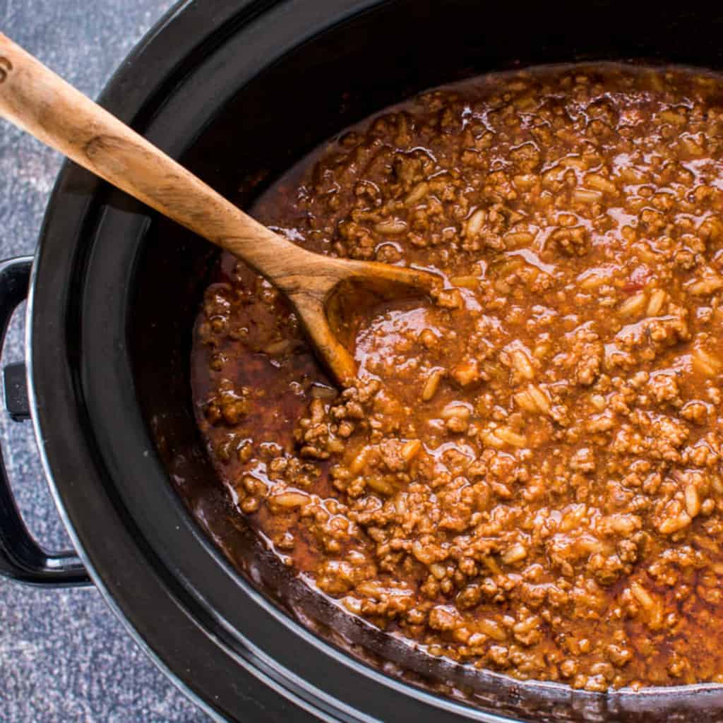 Sloppy Joe mixture in slow cooker with wooden serving spoon