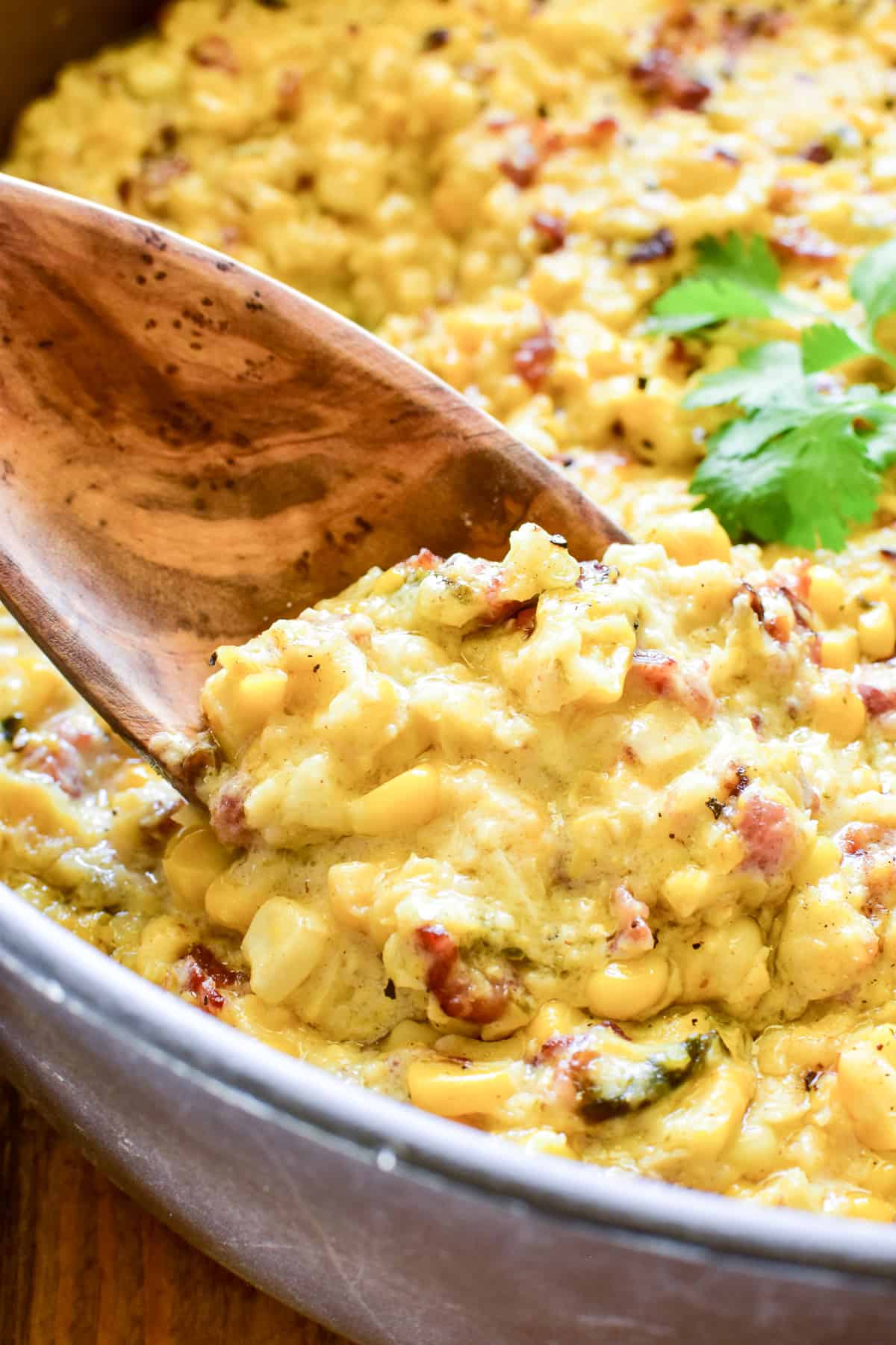 Creamed Corn in a skillet with a wooden spoon