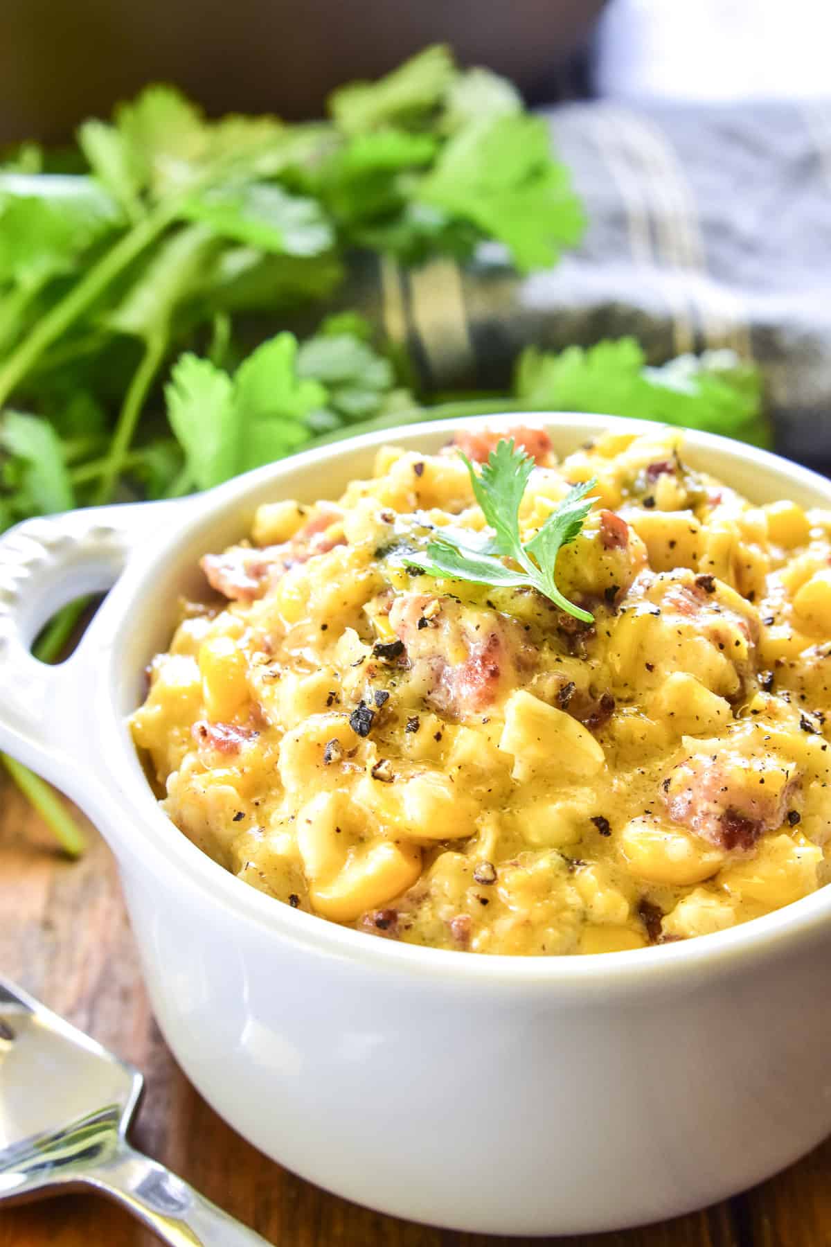 Creamed Corn in a white serving dish with fresh cilantro