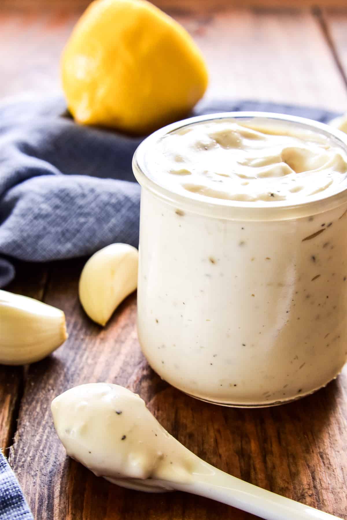 Small spoonful of Garlic Aioli with jar next to it