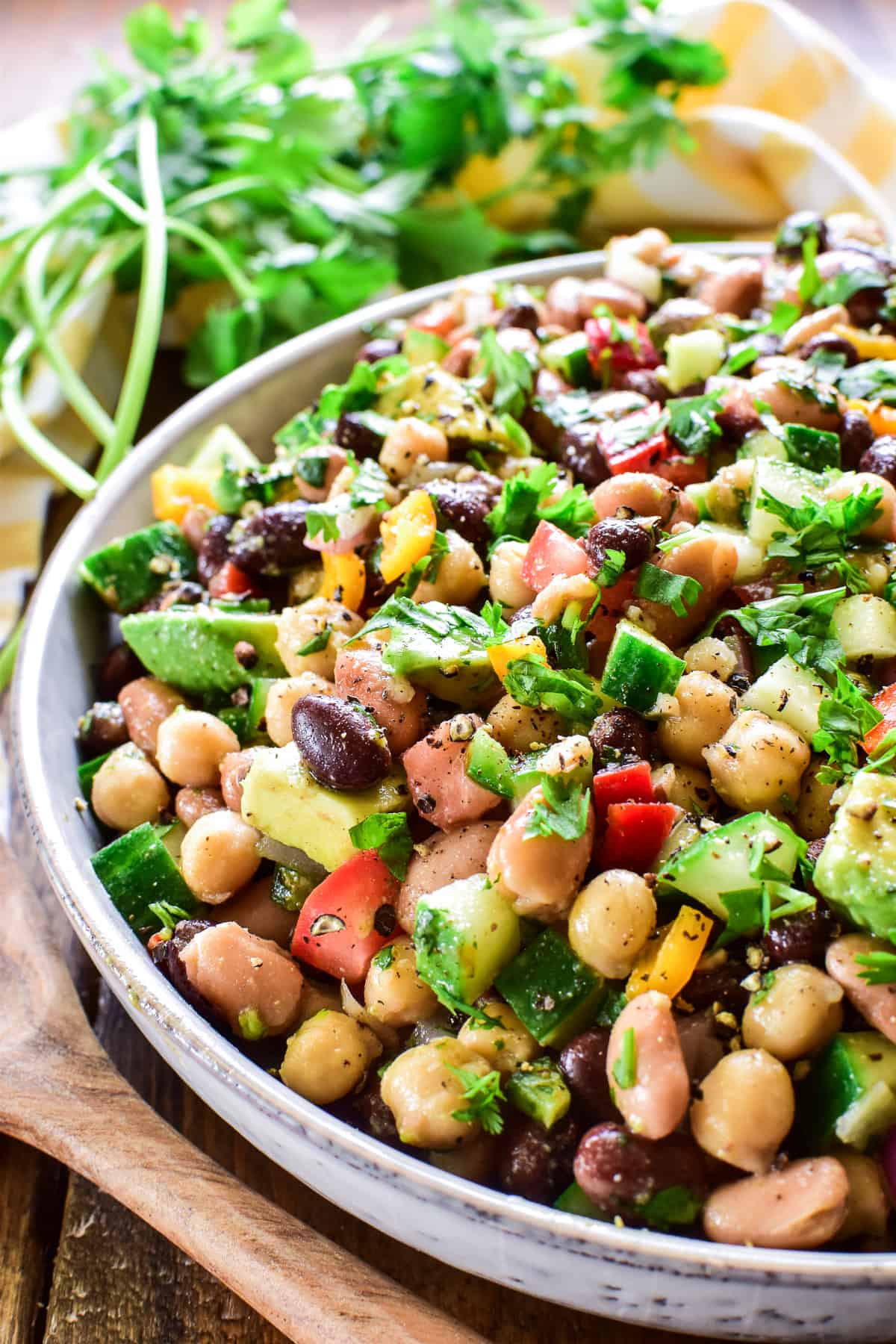 Close up of 3 Bean Salad in a serving bowl with  a wooden spoon