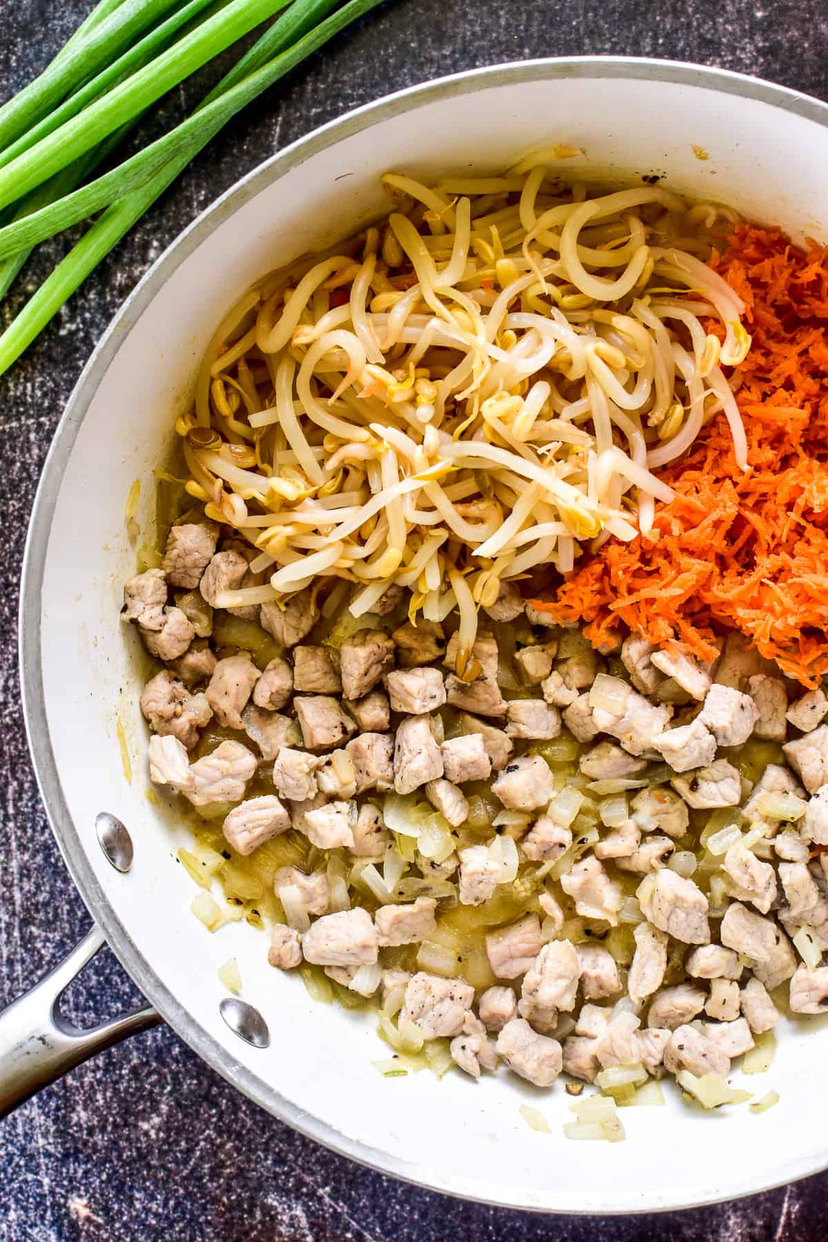 Pork, bean sprouts, onions, and carrots in a skillet 