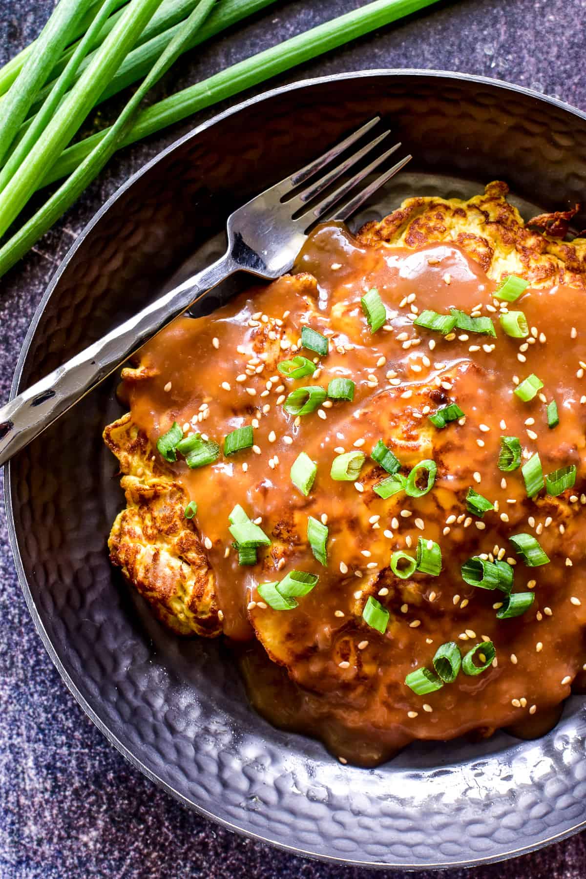 Overhead shot of Egg Foo Young with slicee green onions and sesame seeds