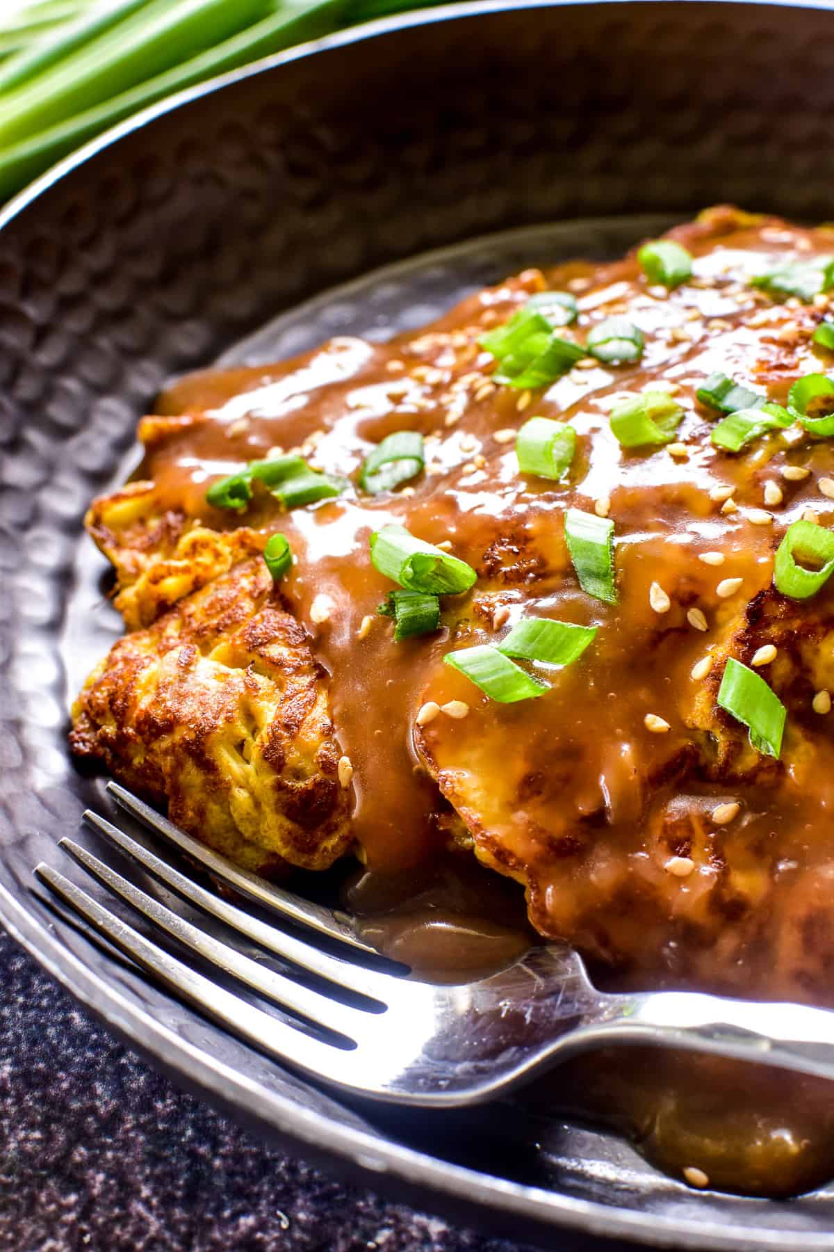 Close up of Egg Foo Young on a dark plate with a fork