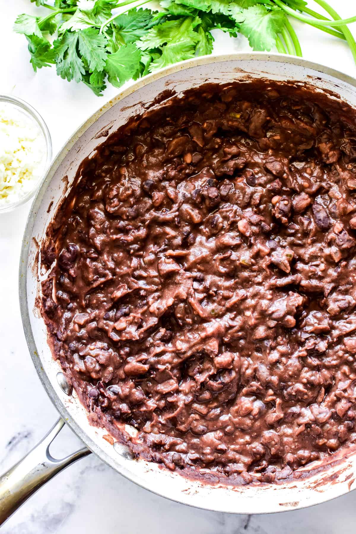 Homemade refried black beans in a white skillet