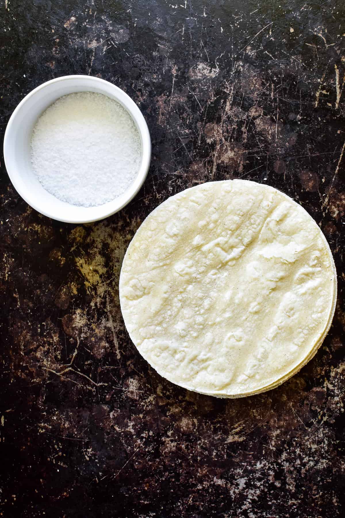 Corn tortillas and salt on a baking sheet