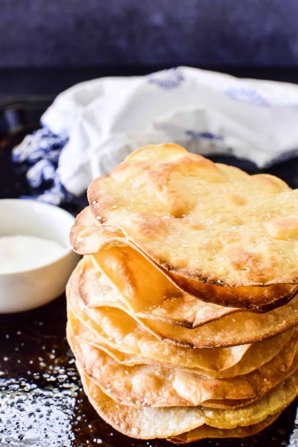 Stack of fresh tostada shells on an oiled baking sheet