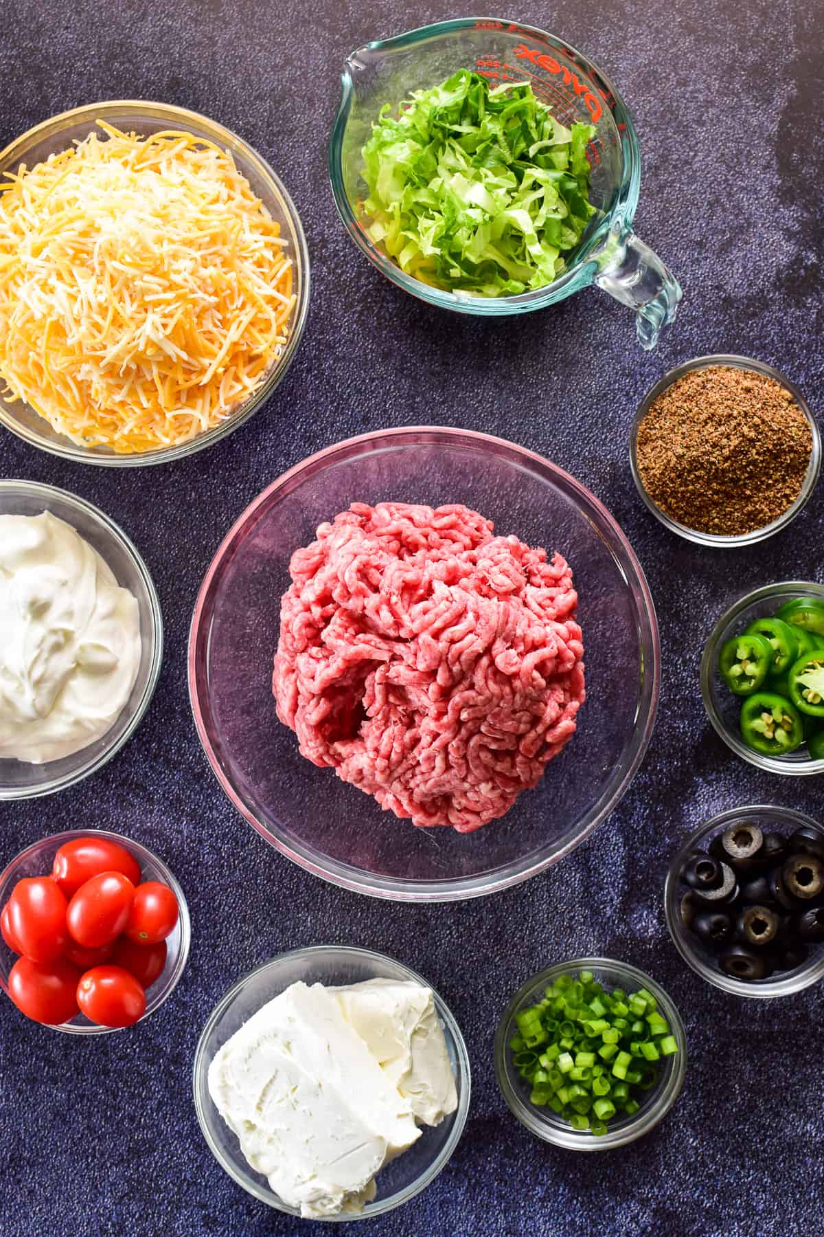 Baked Taco Dip ingredients on a dark background