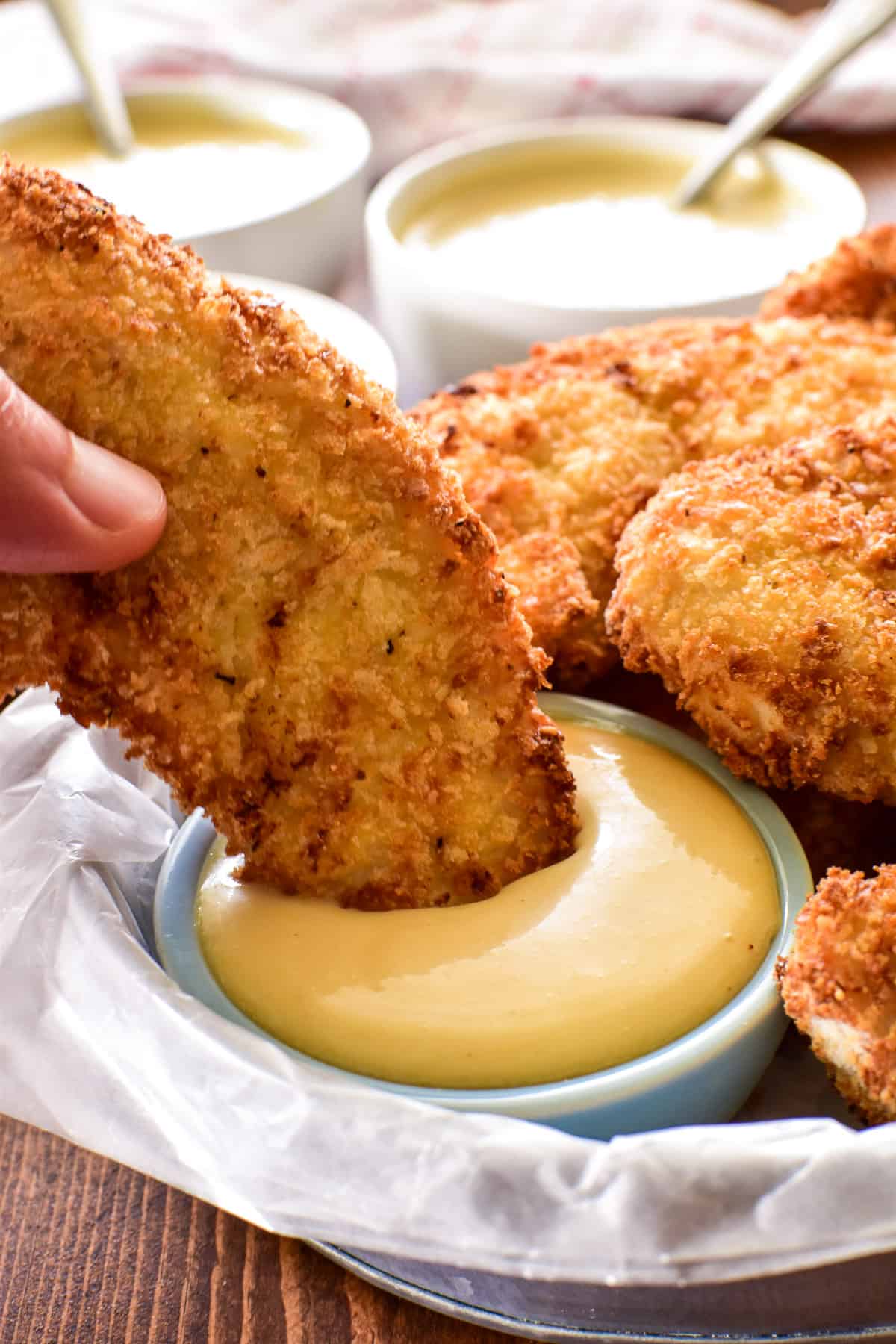 Chicken Tender being dipped into honey mustard