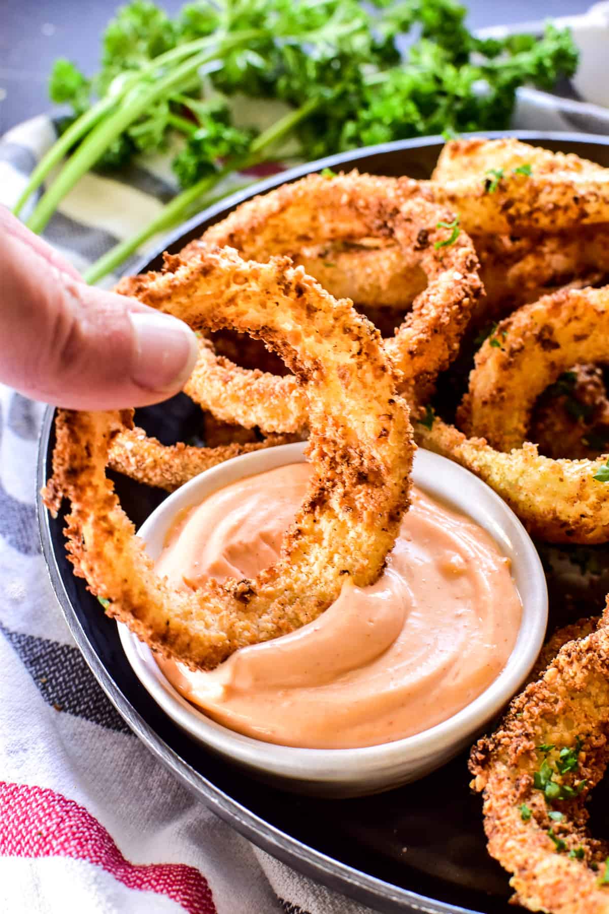 Onion Ring being dipped into sauce