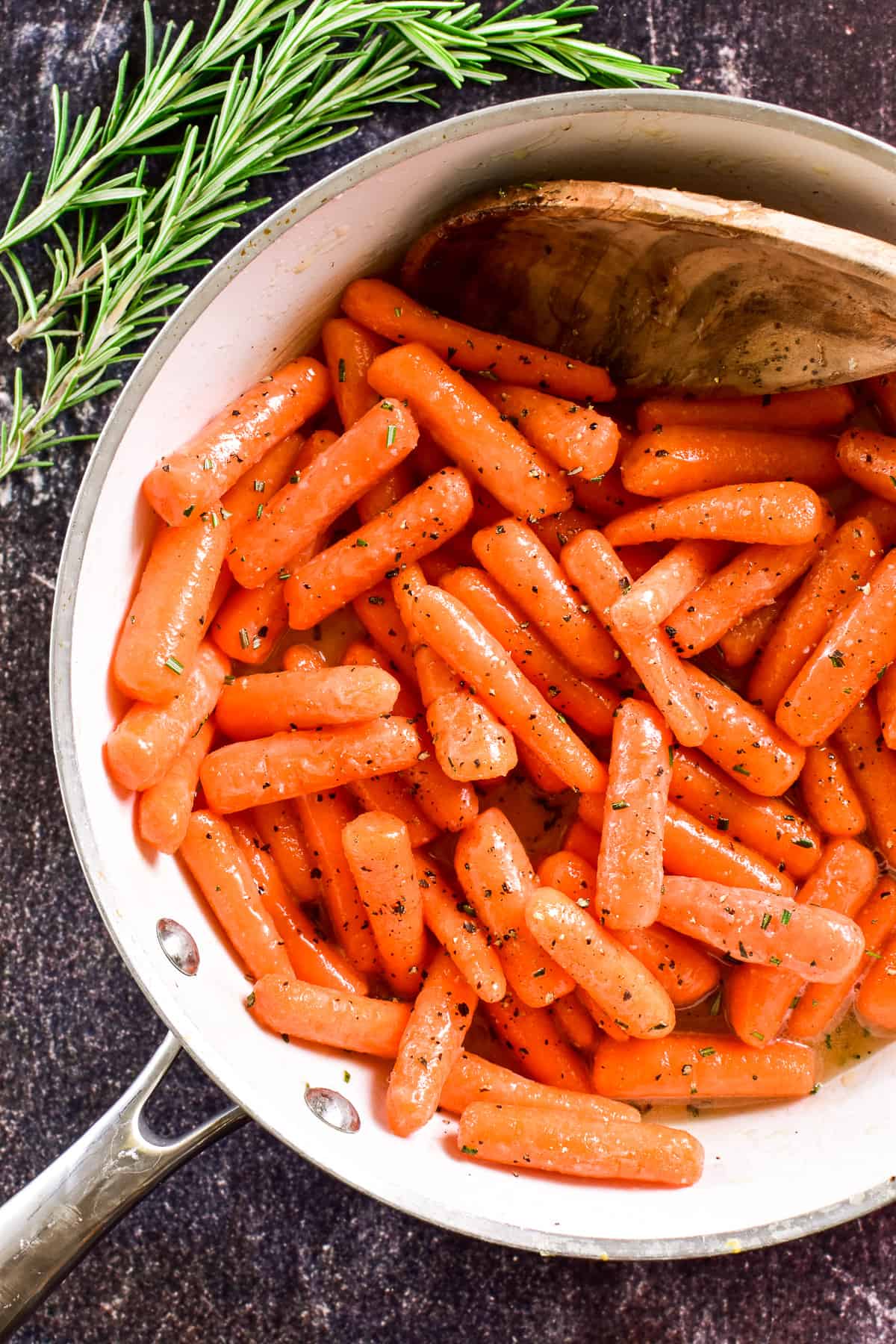 Overhead shot of carrots tossed in honey butter sauce in a white skillet