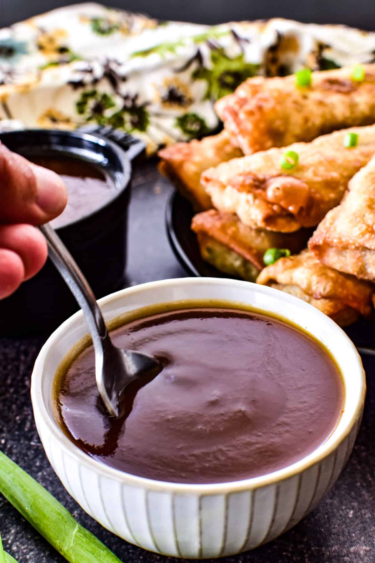 Spoon dipping into Sweet and Sour Sauce in a small white bowl