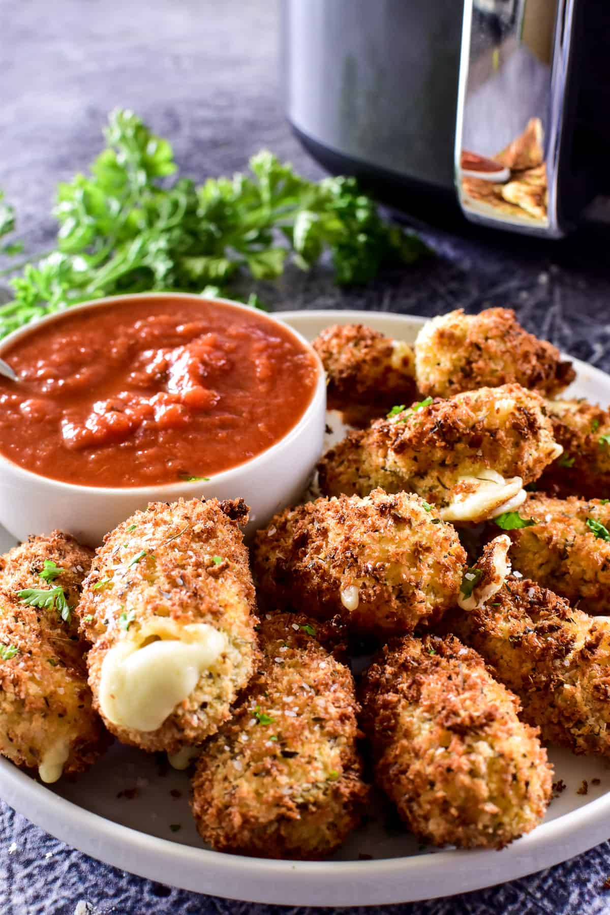 Mozzarella Sticks on a white plate with air fryer in the background