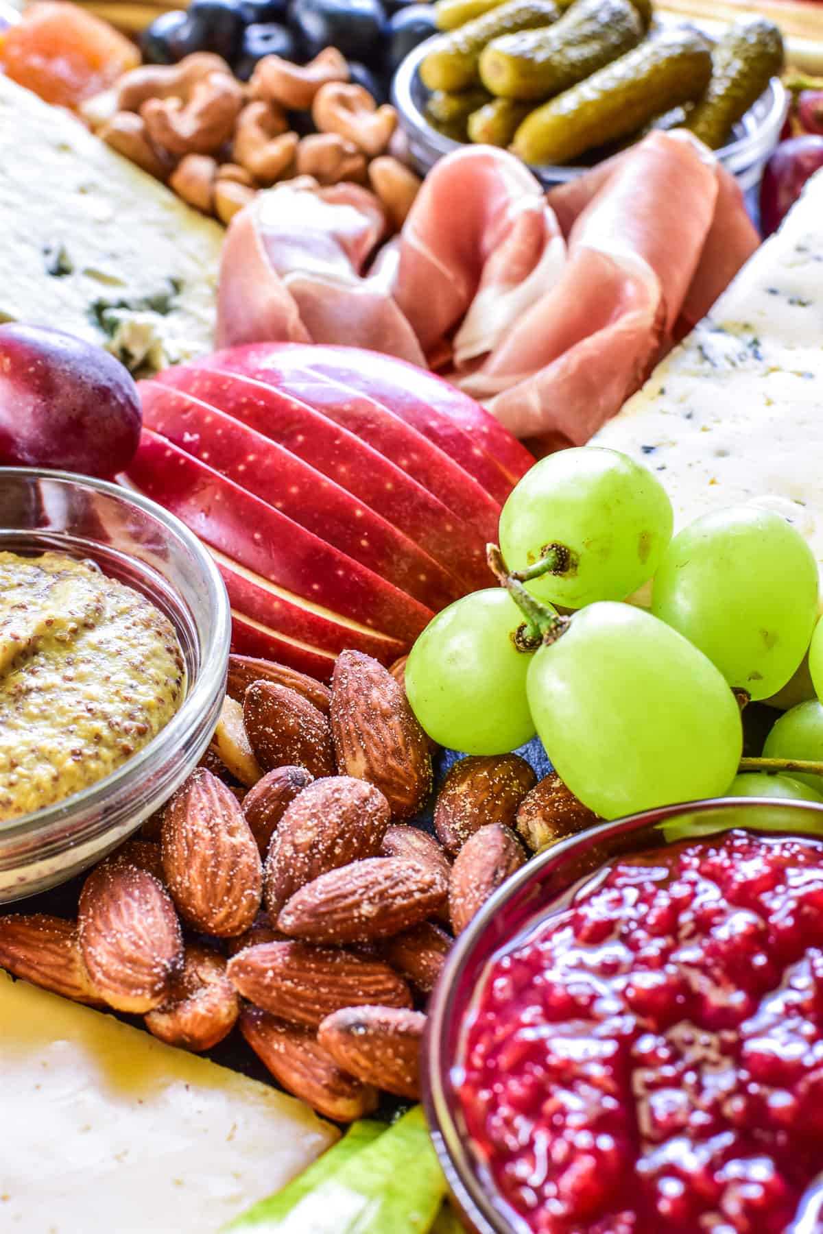 Close up of grapes, apples, almonds, and more on a charcuterie board