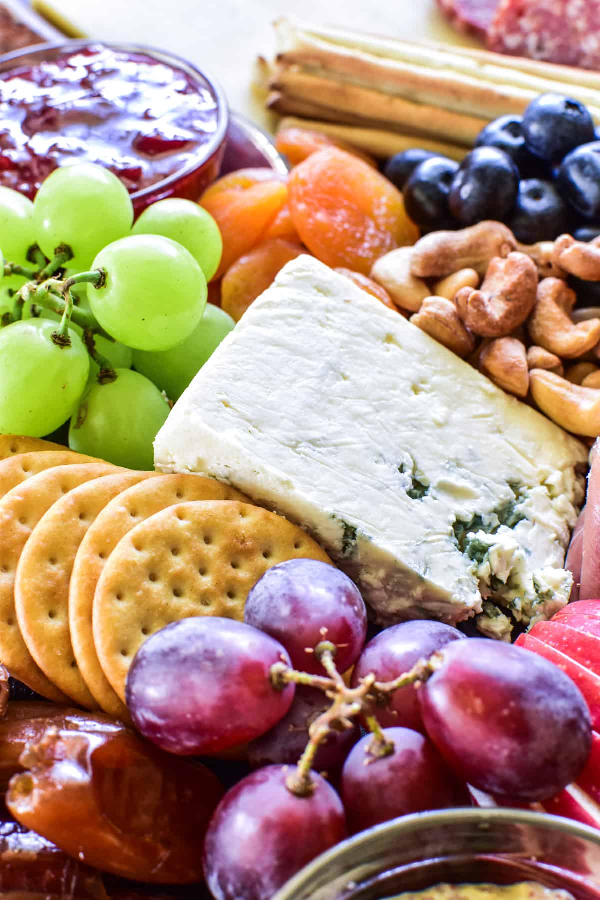 Close up of grapes, cheese, crackers, and more on a charcuterie board