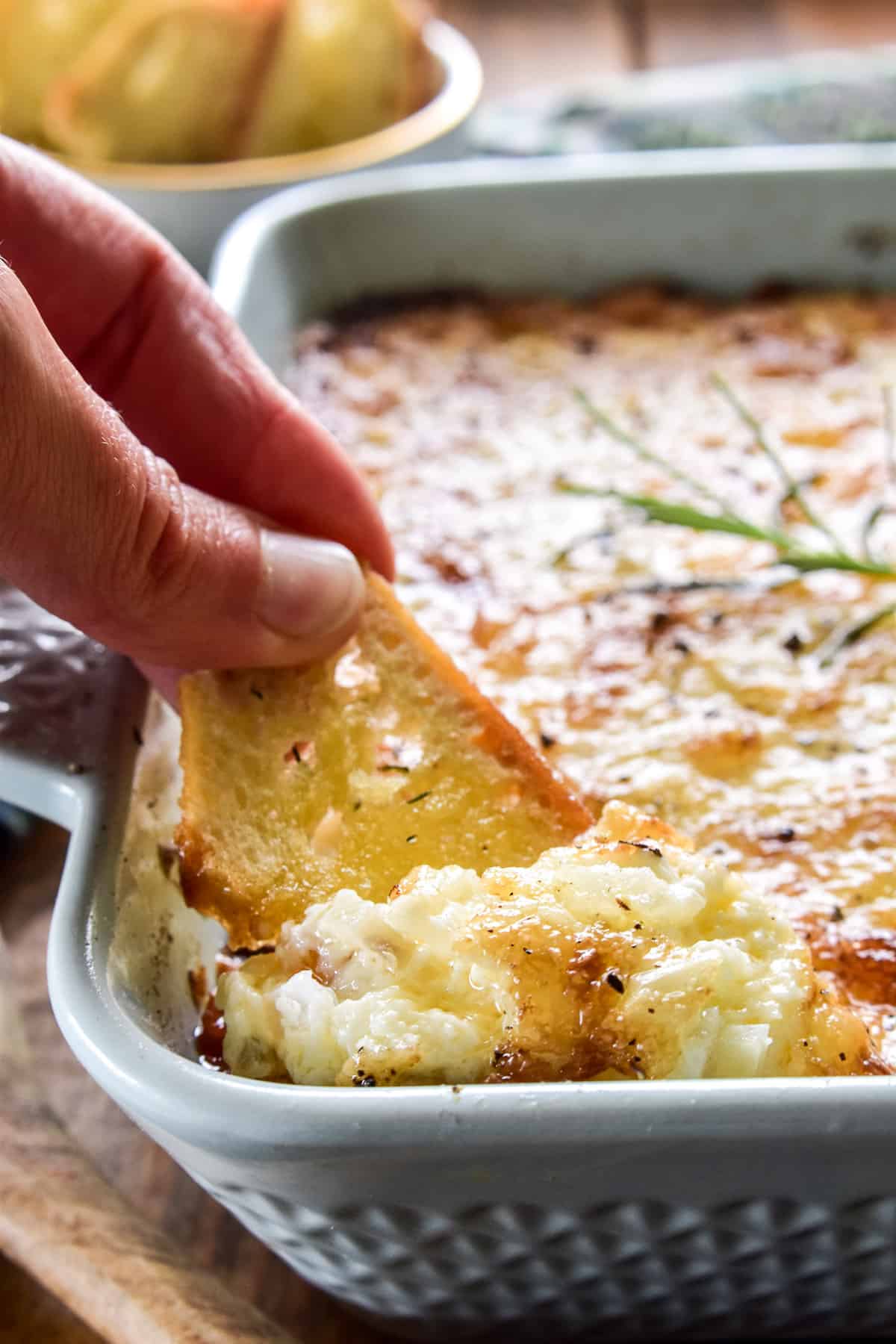 Close up of crostini being dipped into Sweet Vidalia Onion Dip