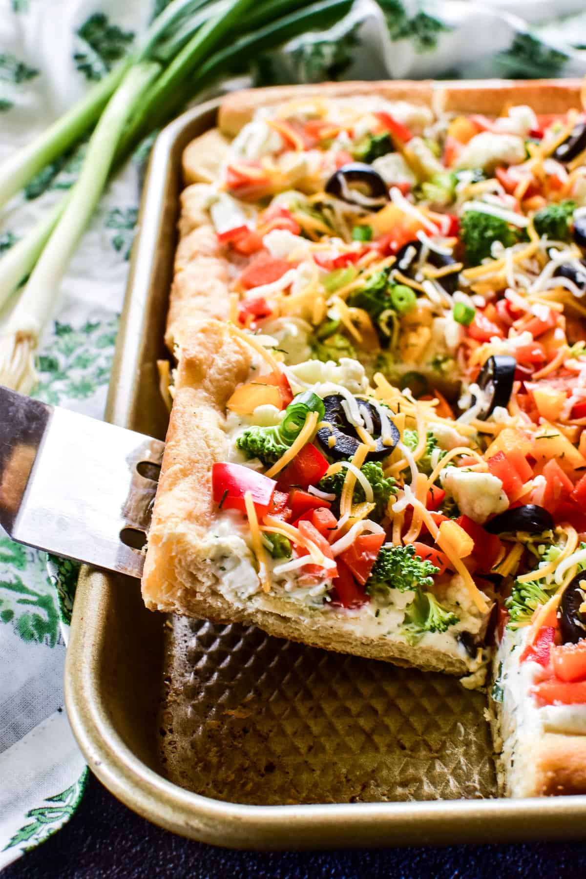 Veggie Pizza in a pan with a slice being served