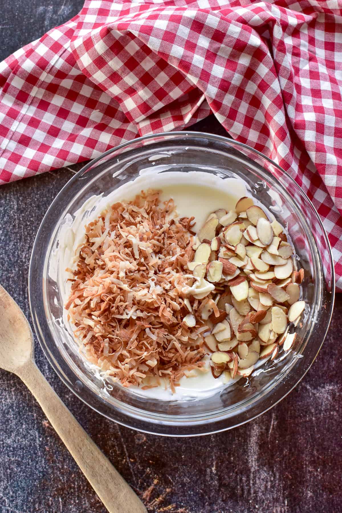 Bowl of melted white chocolate with toasted coconut and sliced almonds