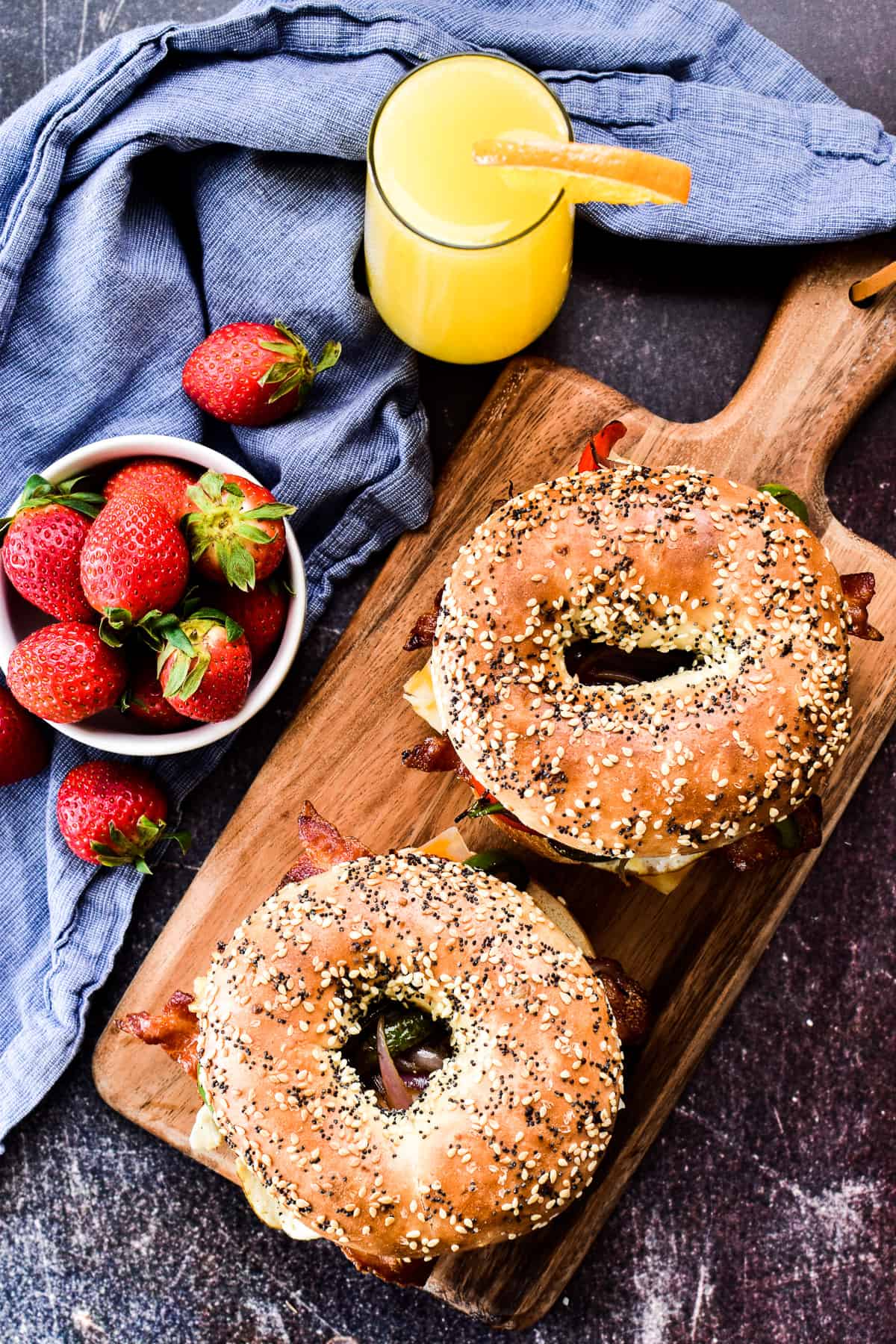 Overhead shot of 2 bagel sandwiches with strawberries & a mimosa