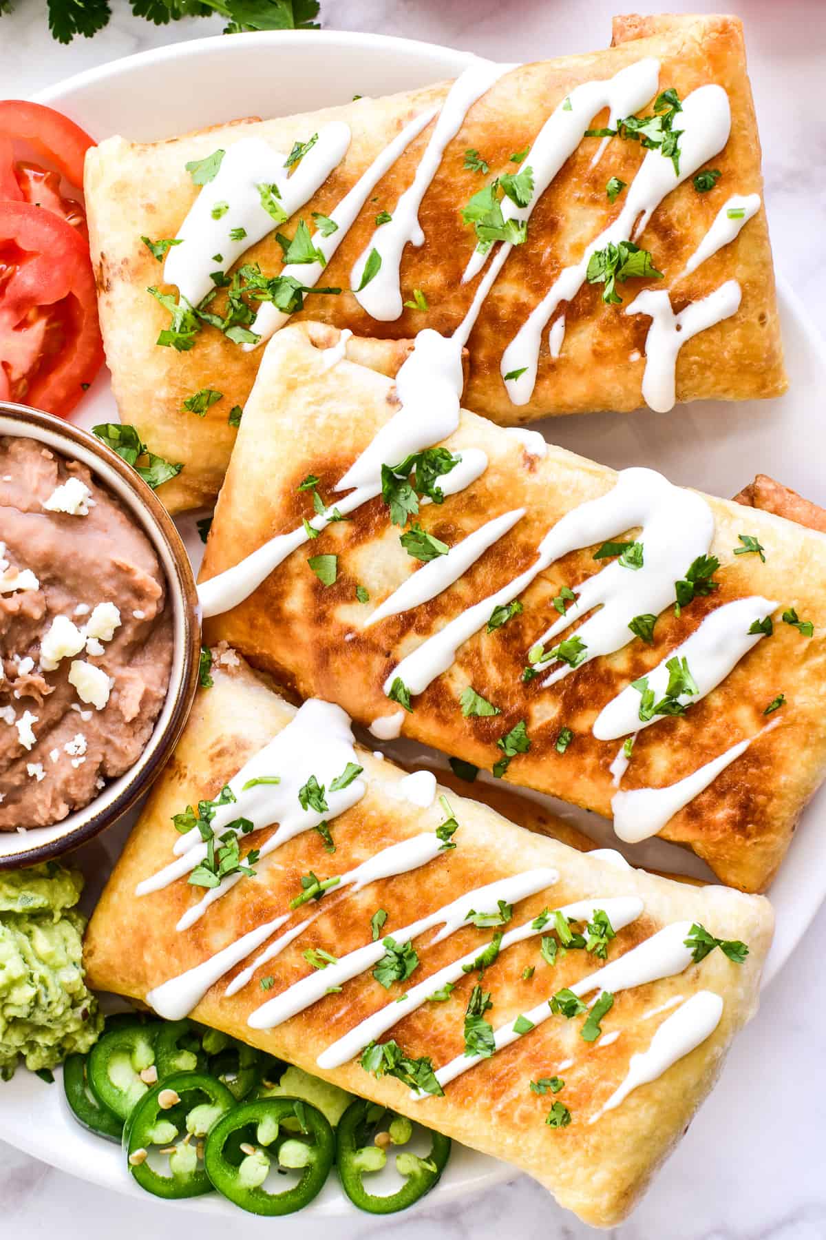 Overhead close up of chimichangas with crema and cilantro