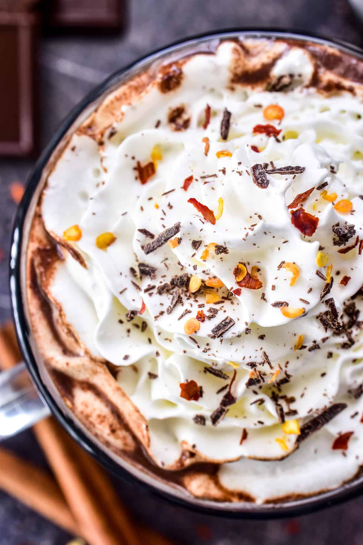 Overhead shot of Mexican Hot Chocolate with whipped cream, chocolate shavings, and crushed red pepper flakes