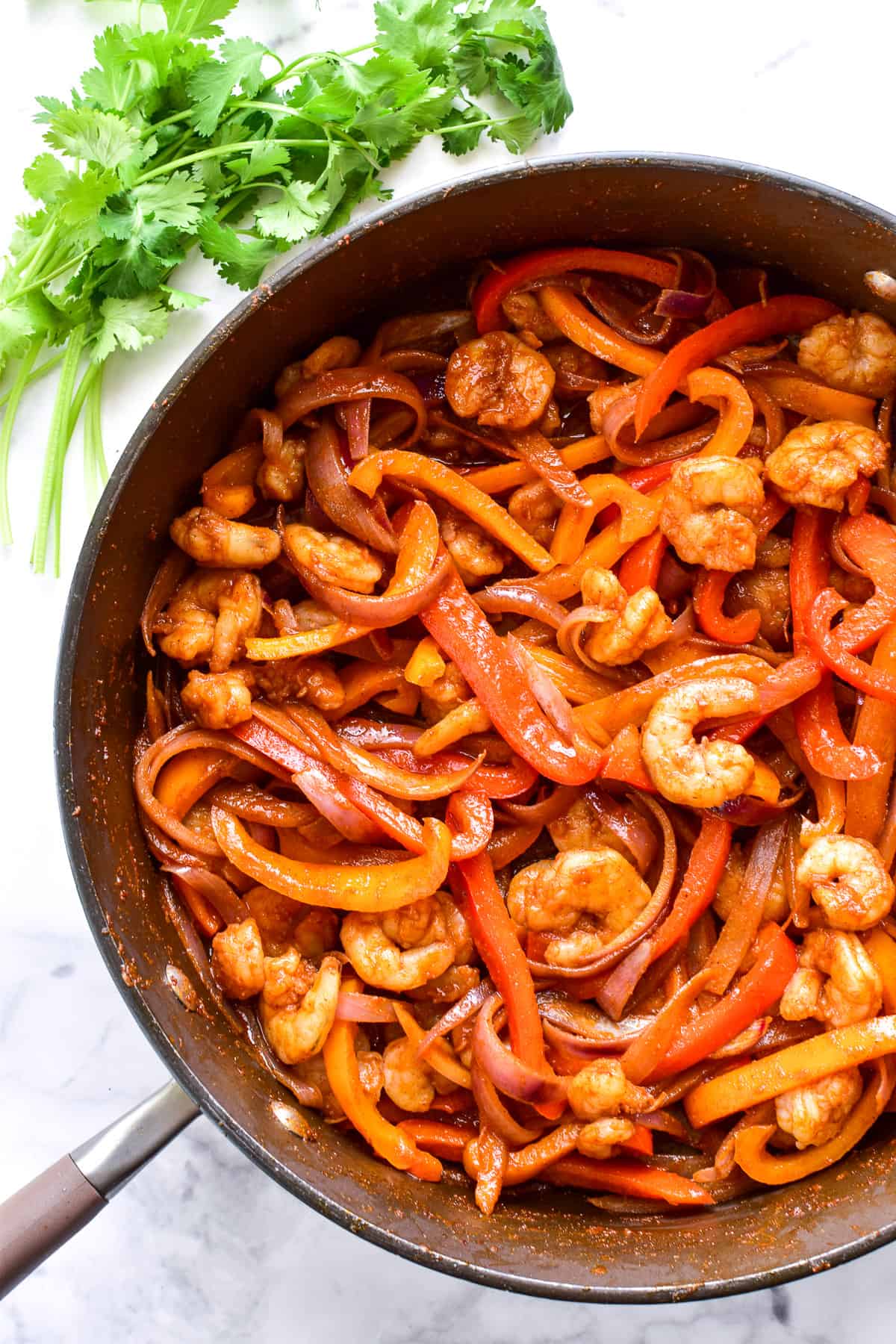 Fajita peppers, onions, and shrimp in a skillet with seasoning