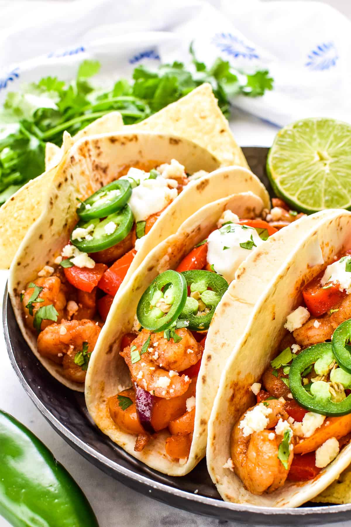 Shrimp Fajitas on a metal serving tray with sliced jalapenos and sour cream