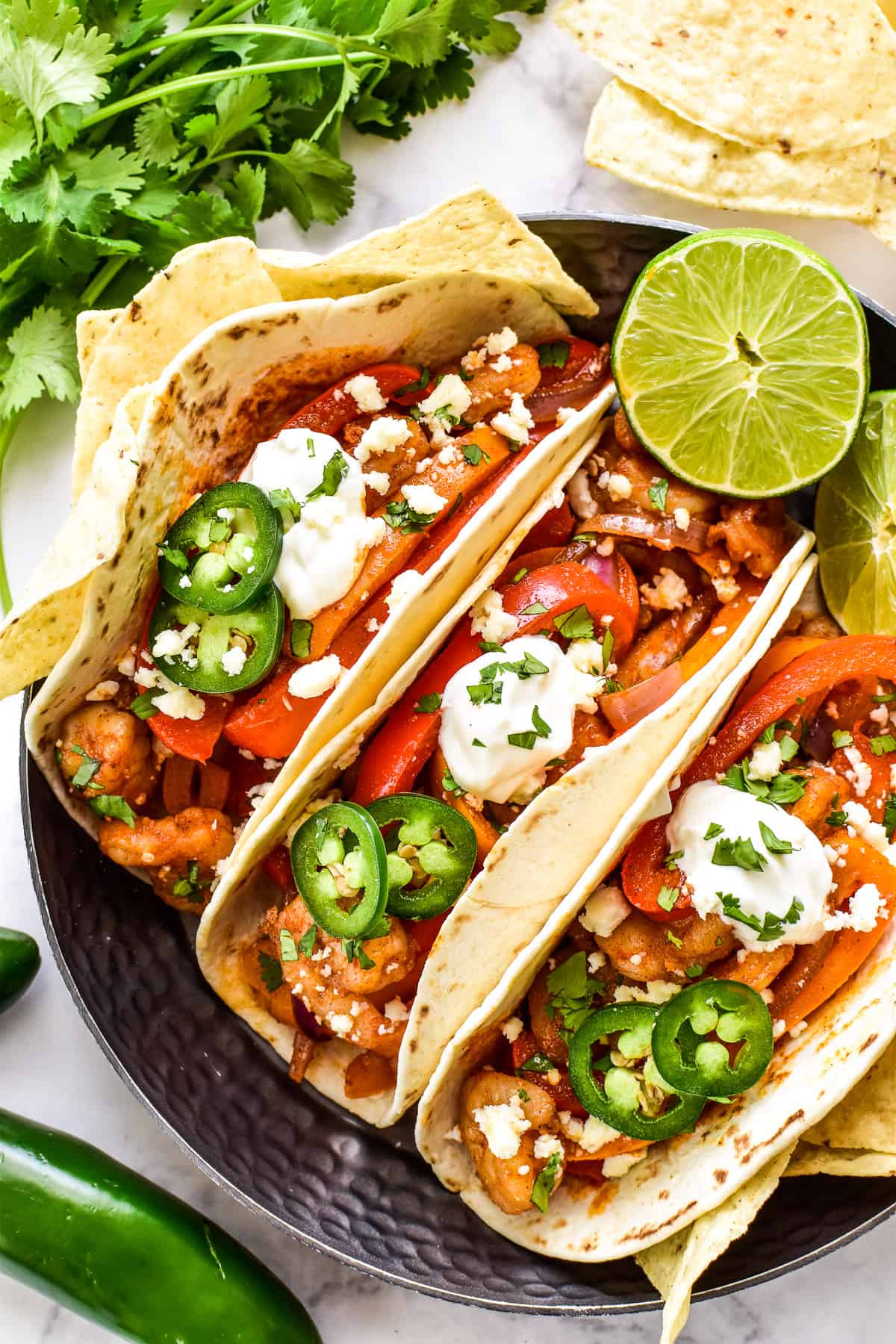 Overhead shot of Shrimp Fajitas with sour cream, jalapeños, queso fresco, and fresh cilantro