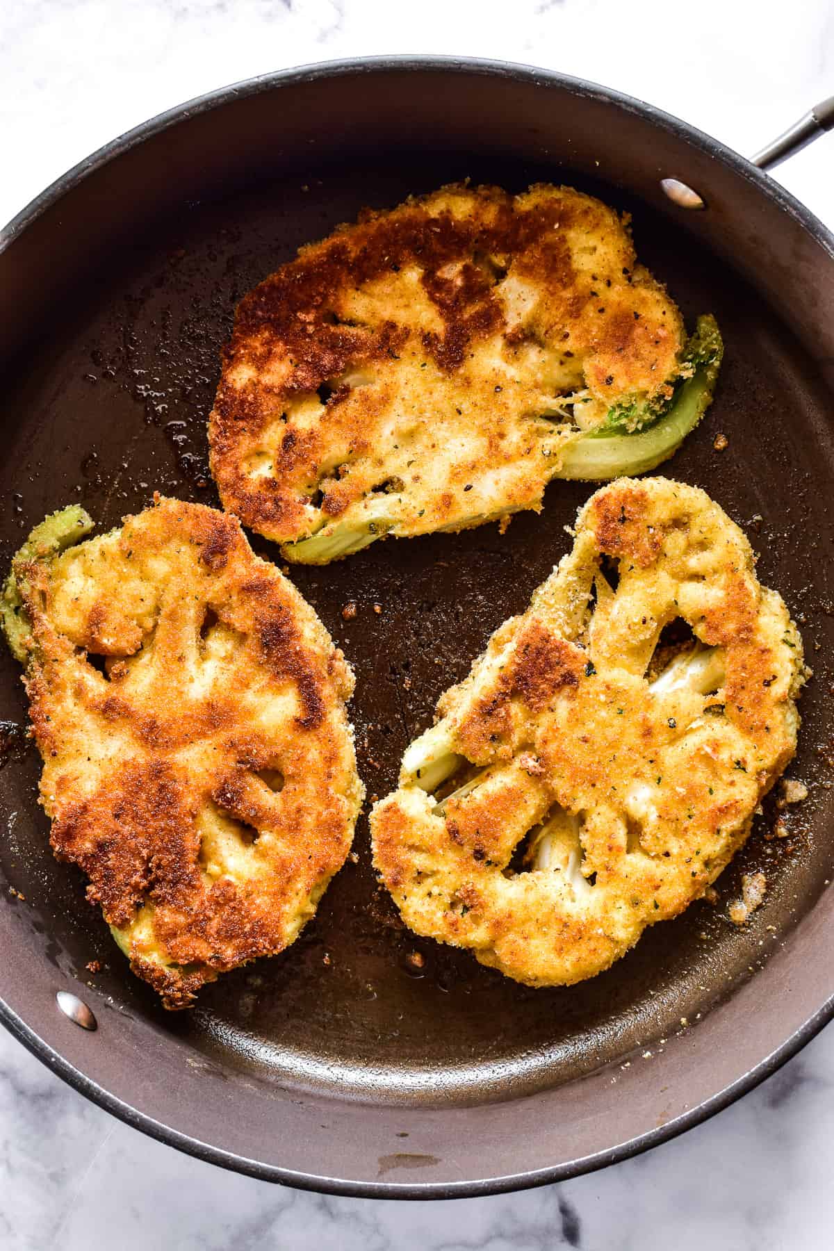 Breaded cauliflower steaks in a skillet