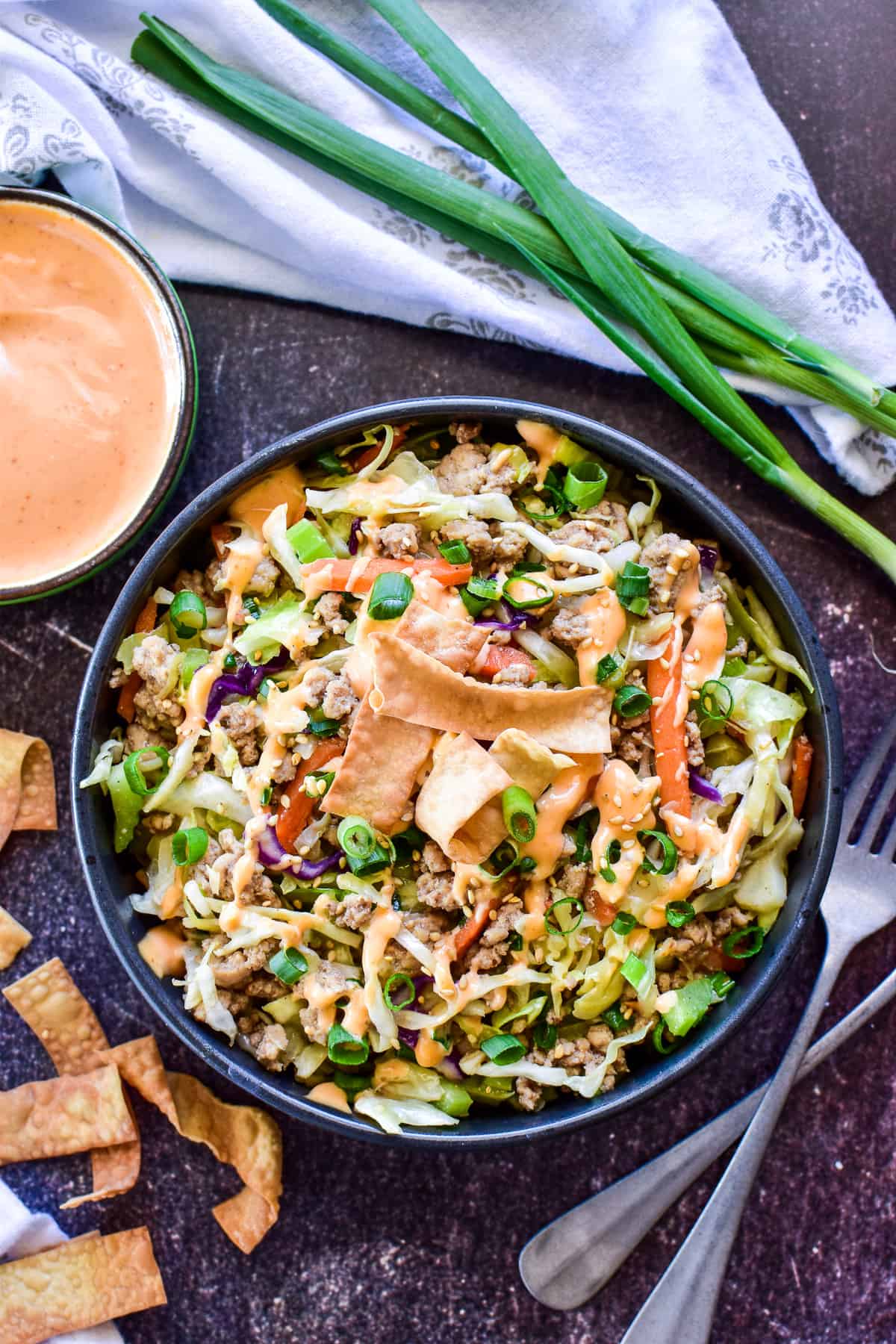 Egg Roll in a Bowl plated with spicy mayo and green onions