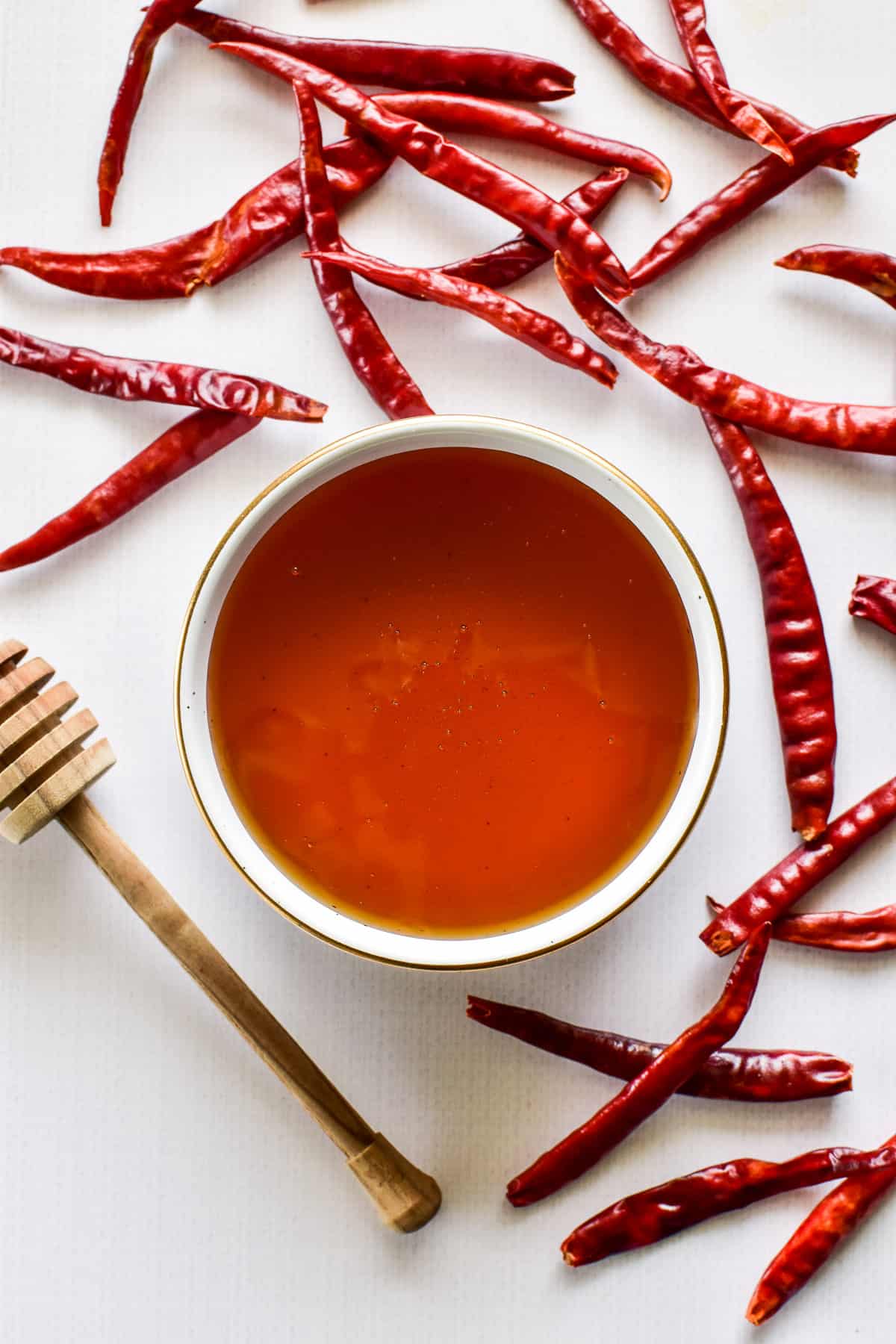 A bowl of honey surrounded by hot chili peppers