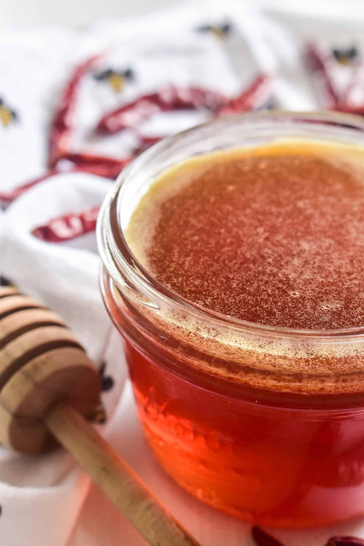 Hot Honey in a small glass jar with a honey dipper