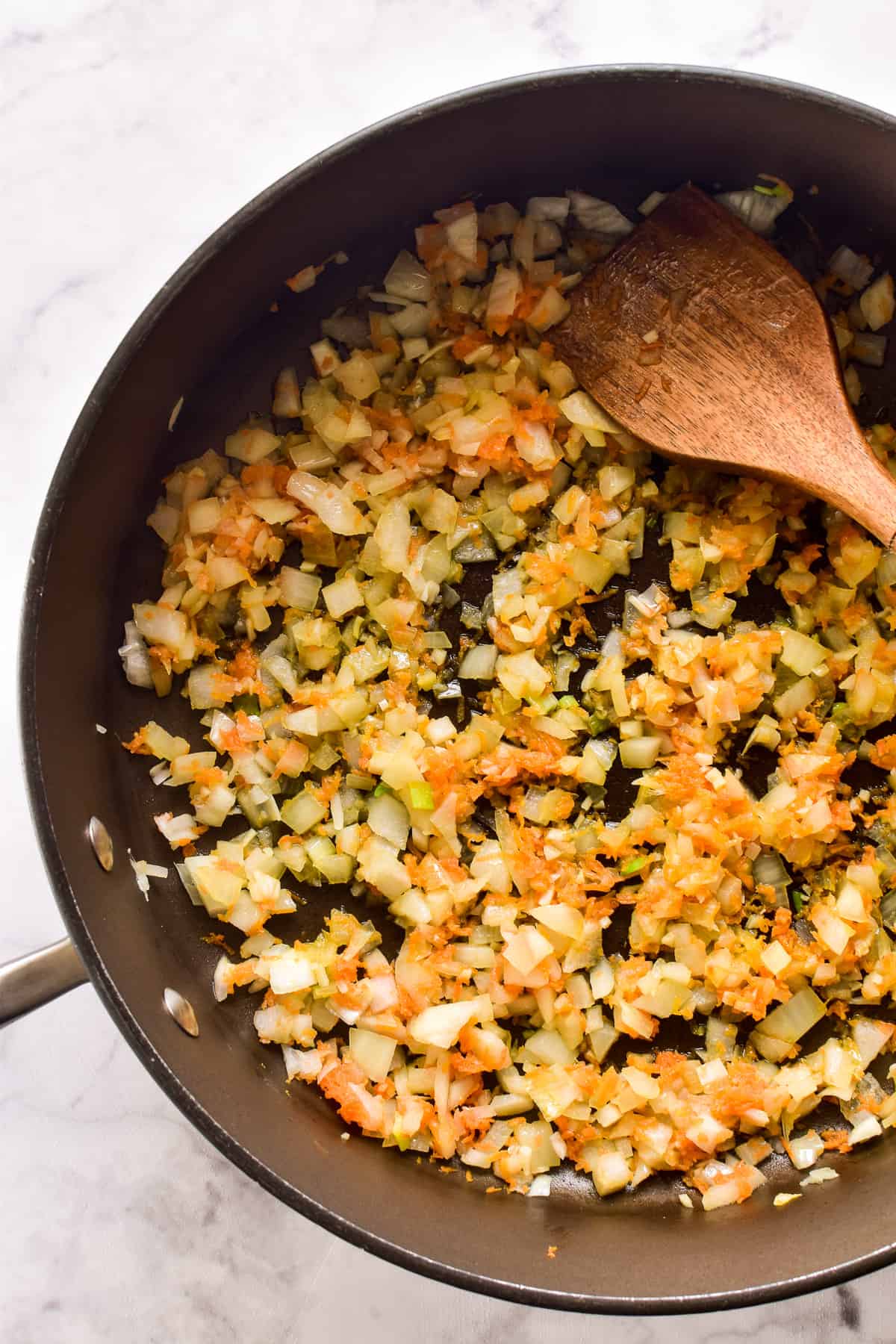 Sautéed onions, garlic, and shredded carrots in a saucepan