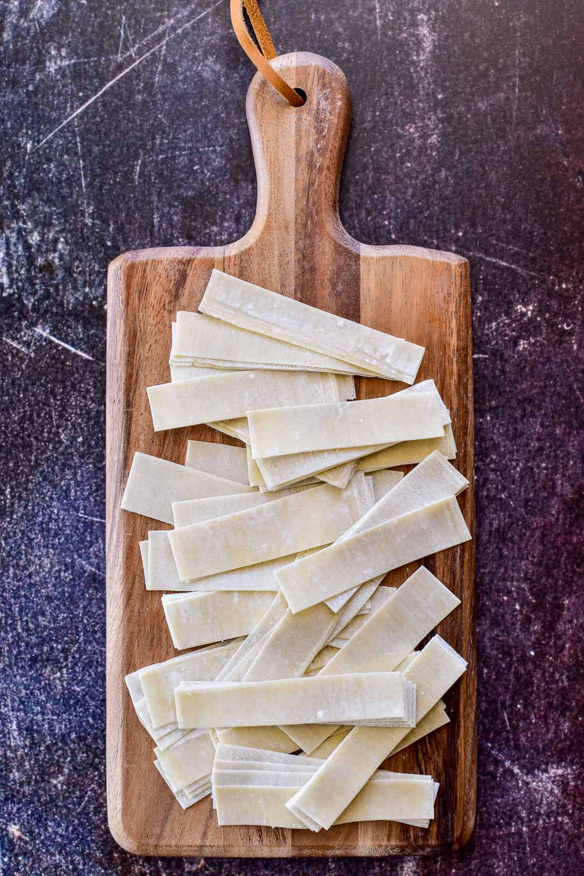 Egg roll wrappers cut into strips on a cutting board