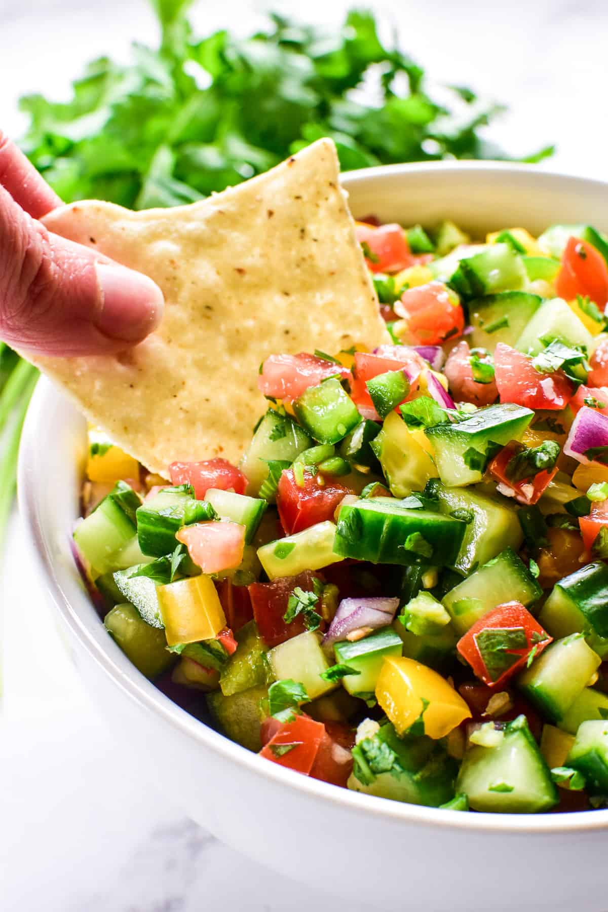 Tortilla chip dipping into Cucumber Salsa