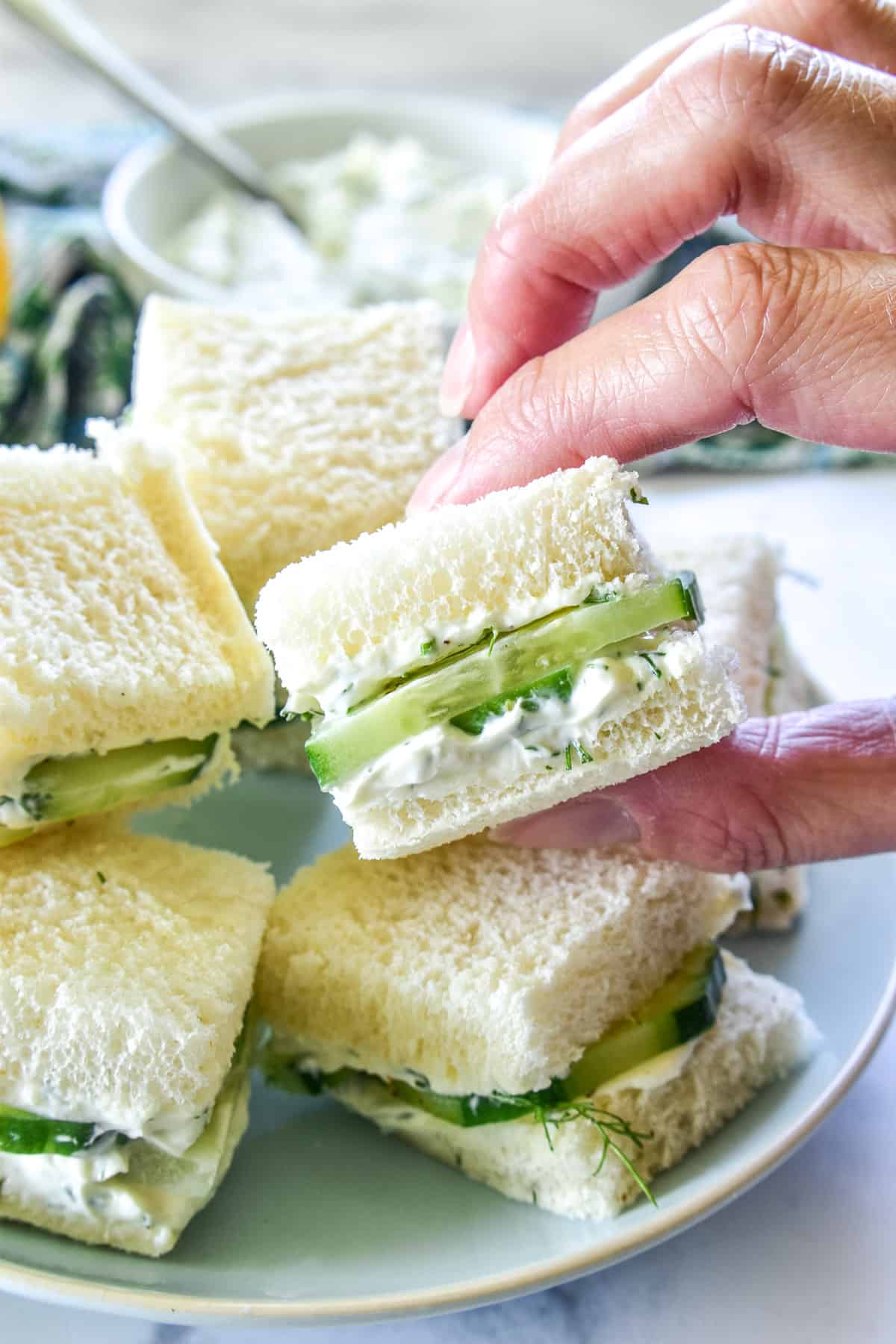 Hand grabbing a Cucumber Sandwich square