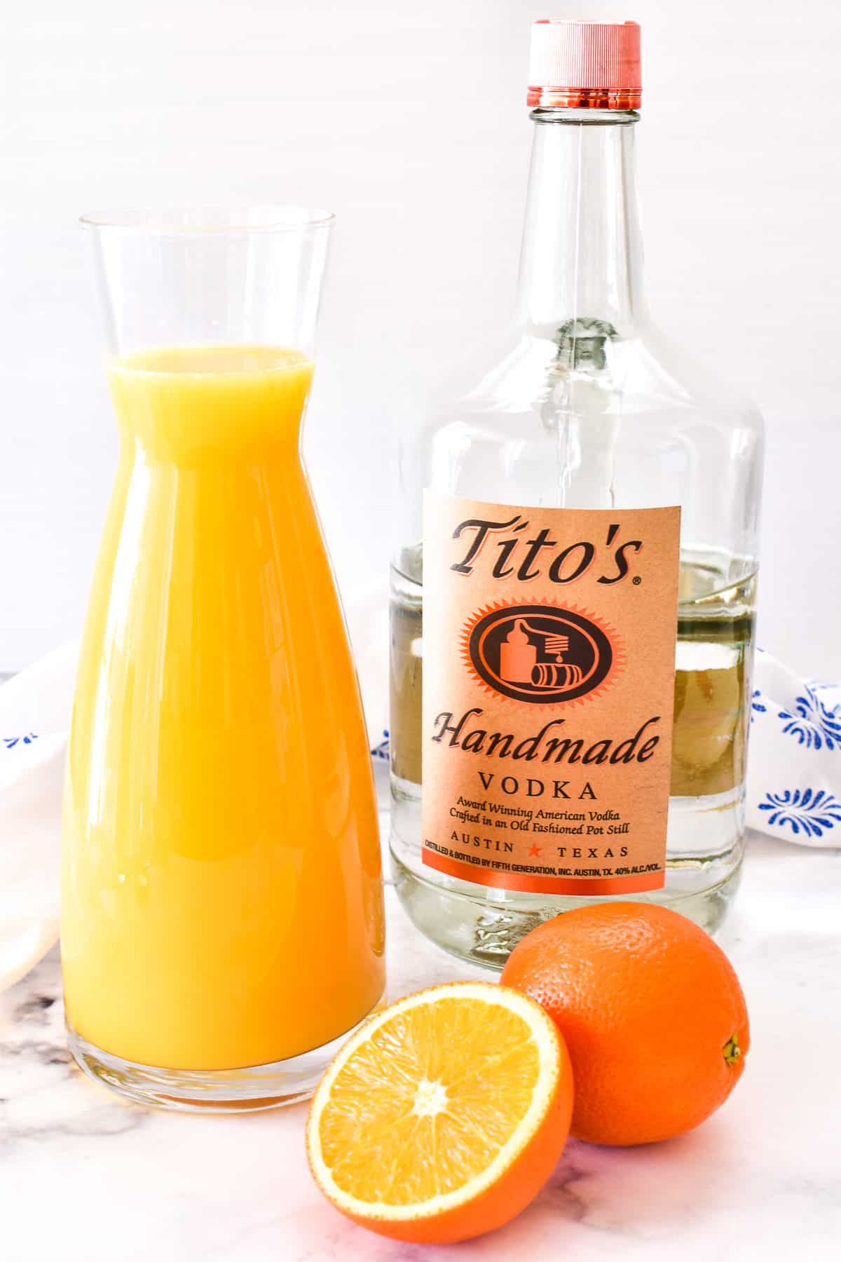 Tito's vodka, orange juice, and fresh oranges