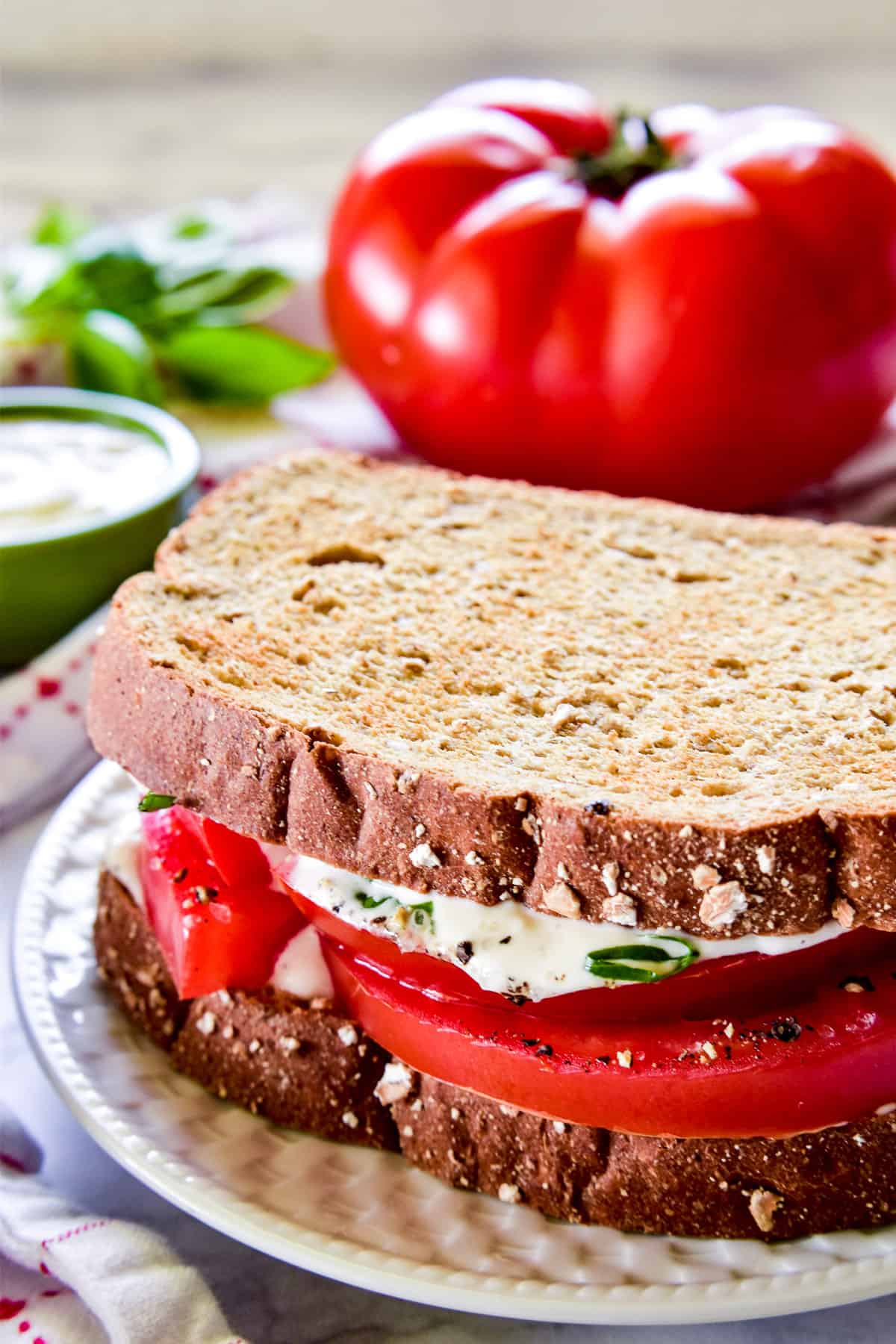 Tomato Sandwich on a white plate with a beefsteak tomato in the background