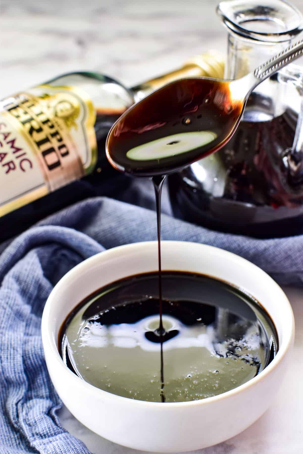 Spoon drizzling balsamic glaze into a small white bowl