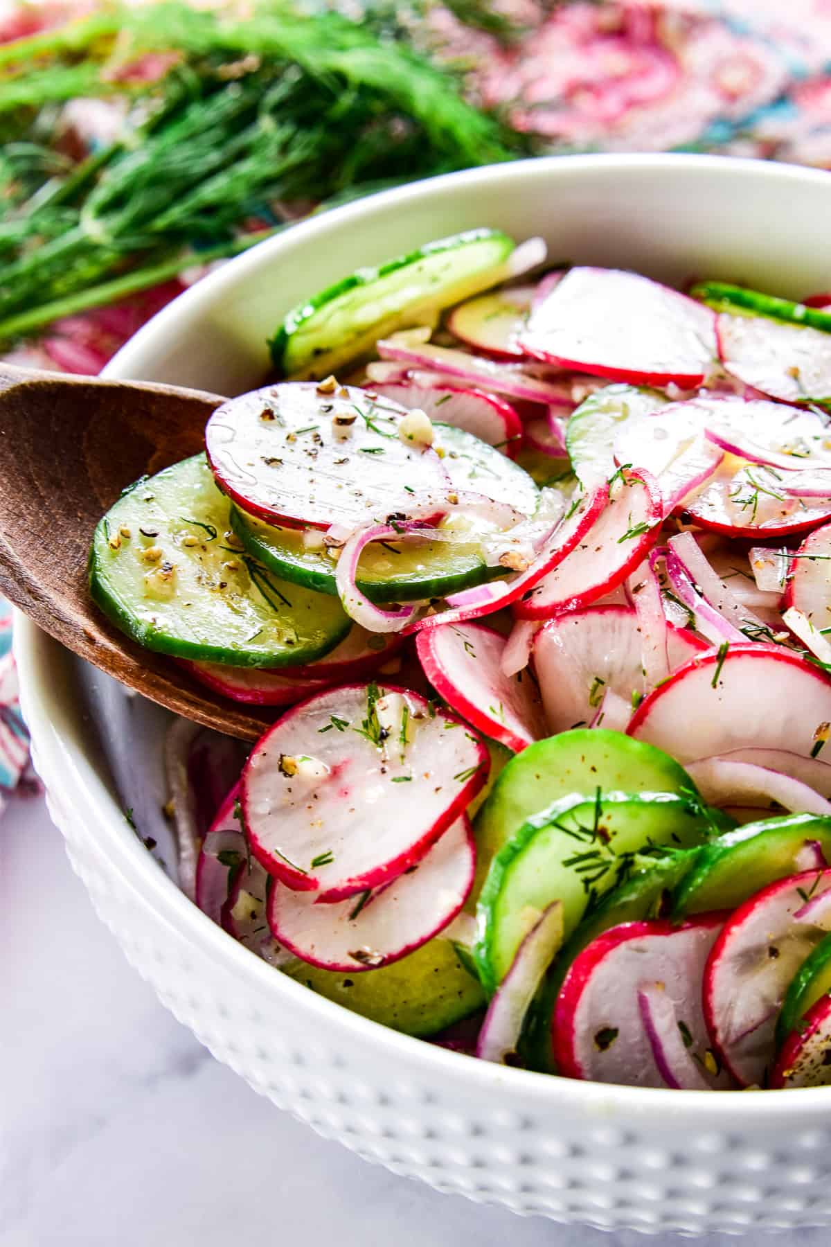 Radish Salad in a white bowl with a wooden serving spoon