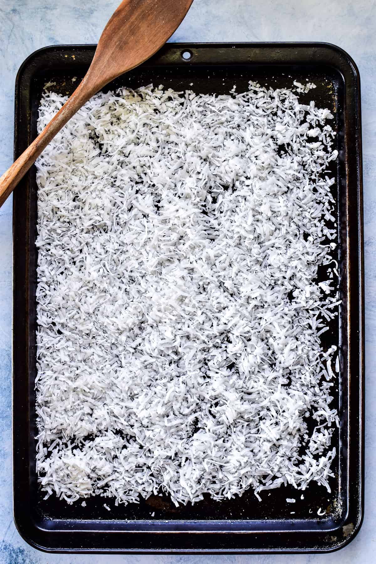 Shredded coconut on a rimmed baking sheet