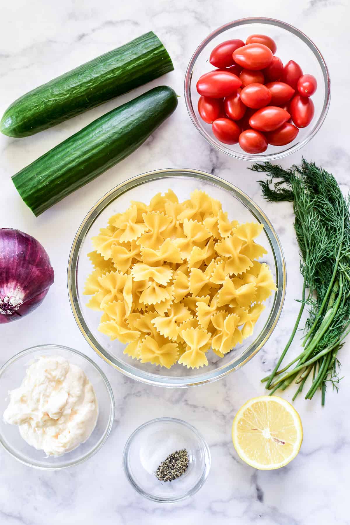 Cucumber Pasta Salad ingredients on a white marble background